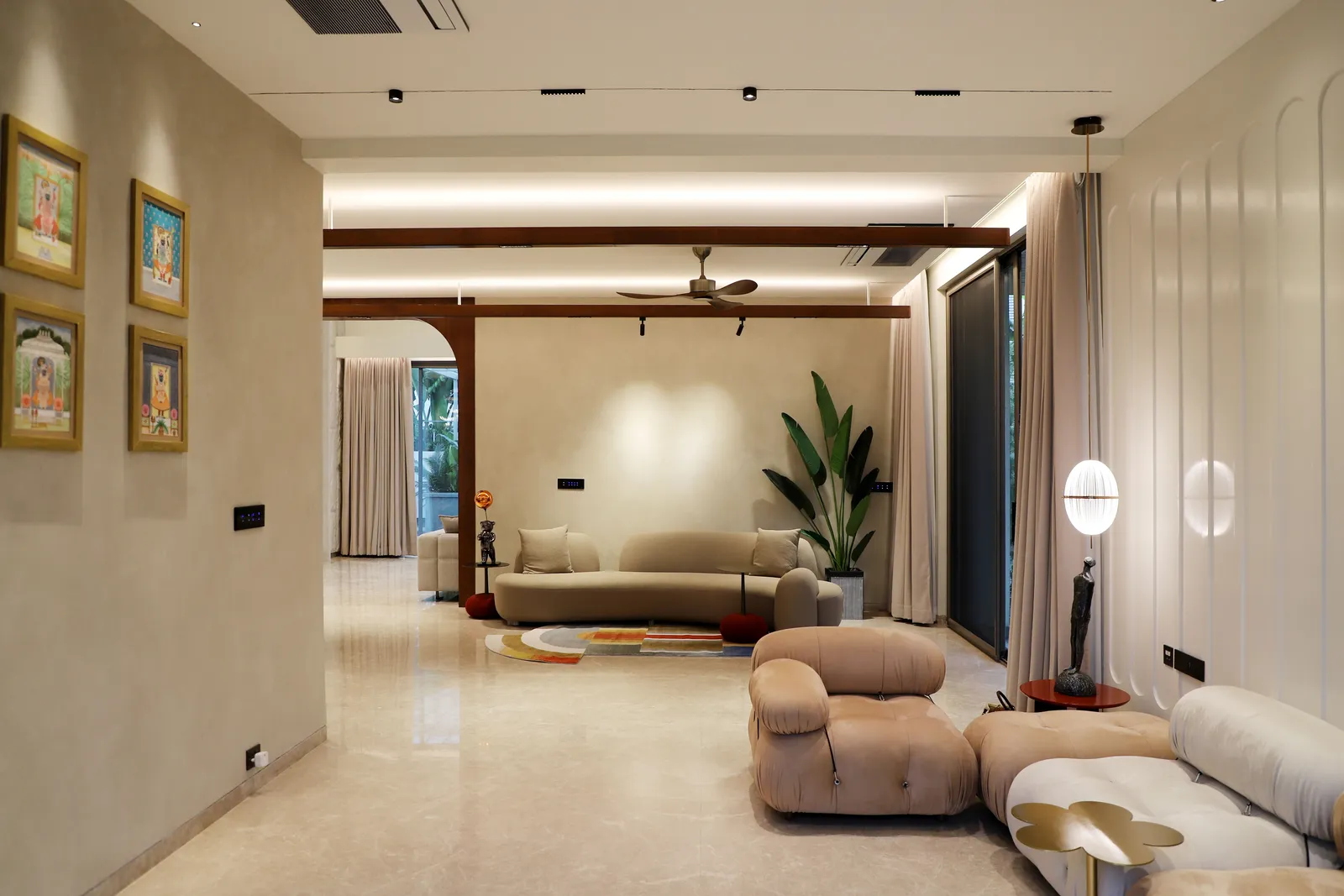 Sala de estar en microcemento beige con vigas de madera y muro ondulado retroiluminado