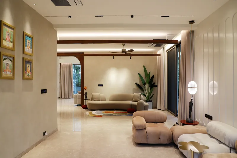 Sala de estar en microcemento beige con vigas de madera y muro ondulado retroiluminado