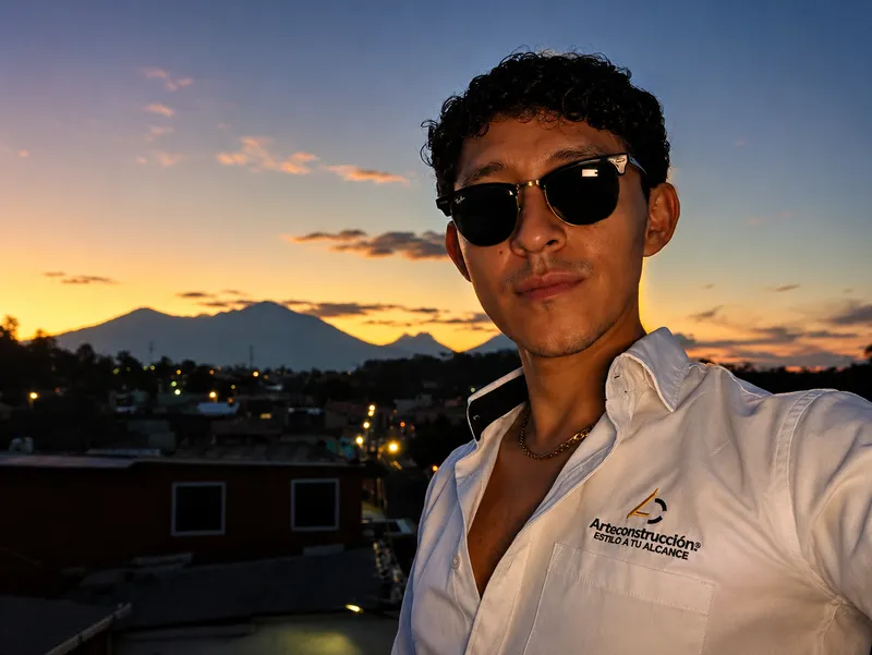 Arq. Erick Morales con camisa de Arteconstrucción frente al atardecer sobre los volcanes de la costa sur