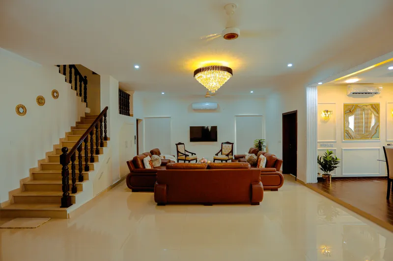 Sala amplia con escalera de madera oscura, candil de cristal y porcelanato claro de formato grande